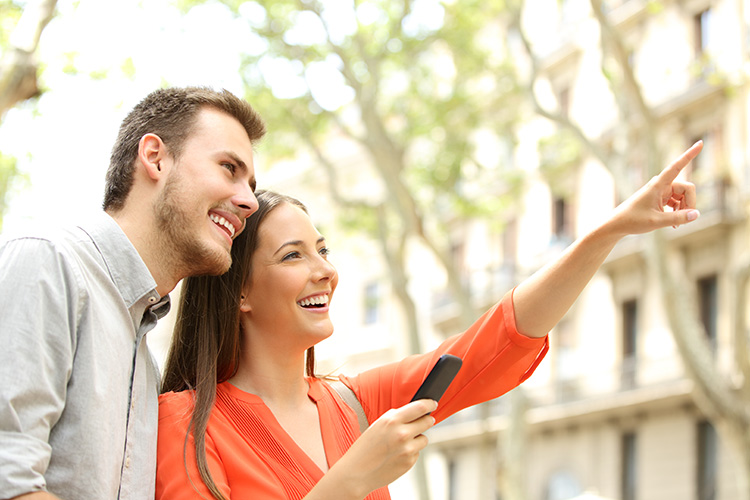 Happy,Couple,Searching,Home,Location,With,The,Mobile,Phone,In